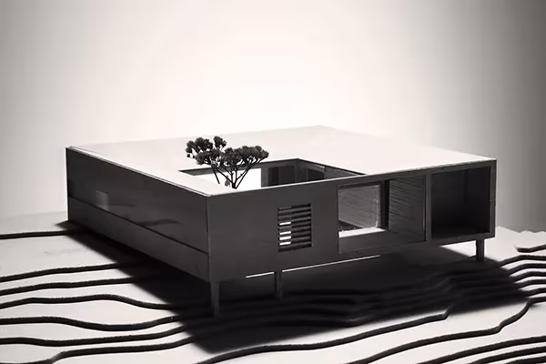 Maqueta negra de la Casa Cubo de Reiulf Ramstad con patio central y un árbol, sobre curvas de nivel