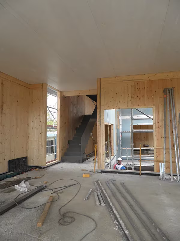 Interior en obra de una Casa Eficiente de ÁBATON con muros de madera maciza y escalera a la vista