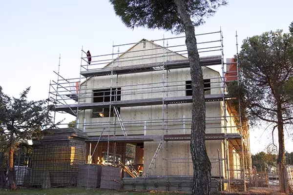 Casa Eficiente de ÁBATON de cubierta a dos aguas rodeada de andamios entre pinos
