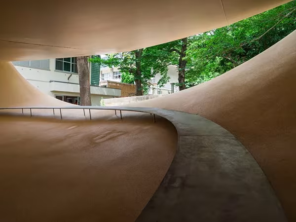 Dos planos curvos del Fukita Pavilion de Ryue Nishizawa abiertos hacia los árboles y edificios del entorno