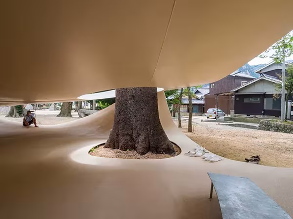 Interior del Fukita Pavilion con el árbol en un hueco de arena y una persona sentada al fondo
