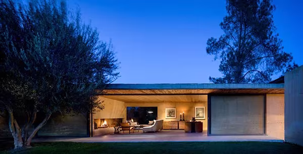 NAPA House de Steven Harris al anochecer, con el salón iluminado bajo una cubierta plana entre árboles