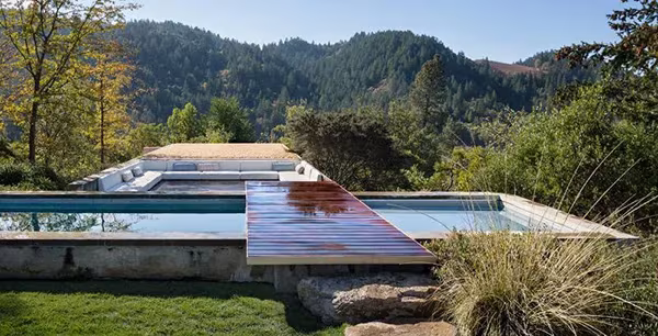 Piscina alargada de la NAPA House con pasarela de madera y cubiertas planas ante las montañas de Napa