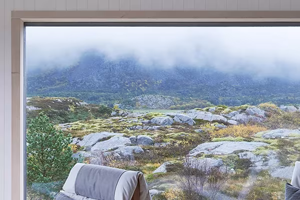Ventanal de la Vega Cottage que enmarca rocas de granito y montañas con nubes bajas