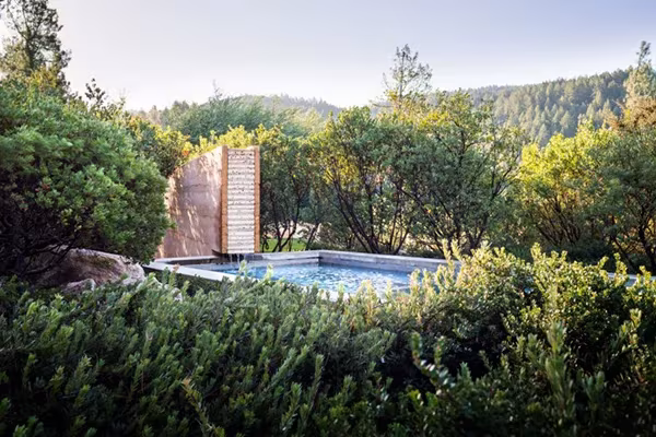 Piscina de la NAPA House de Steven Harris entre arbustos y encinas, con un muro de madera y colinas al fondo