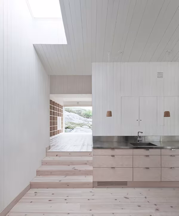 Cocina blanca de la Vega Cottage con lucernario, encimera de acero y suelo de pino claro