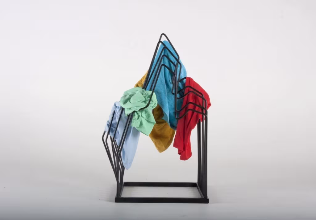 Estructura de varillas negras con forma de silueta de silla sobre la que cuelgan prendas de colores