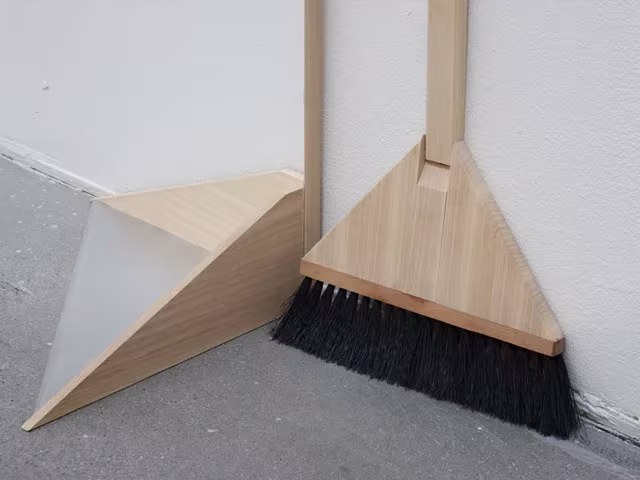 Escoba de madera junto a una pieza triangular que materializa el vacío de su forma, de Konstfack