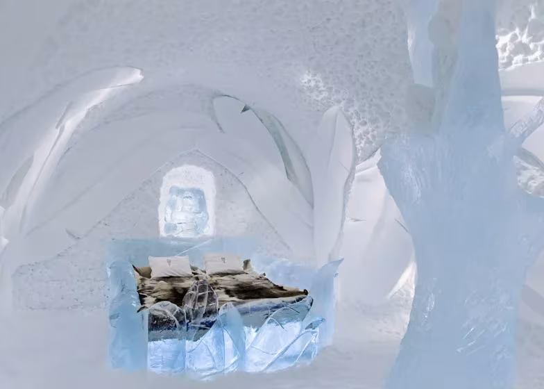 Habitación del Icehotel de Jukkasjärvi con cama de hielo cubierta de pieles y paredes de nieve esculpida