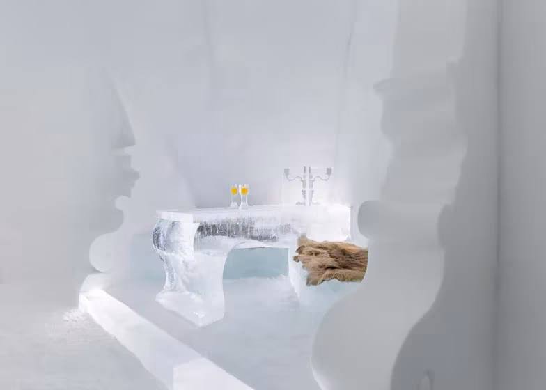 Habitación de nieve del Icehotel con banco y mesa de hielo, pieles y paredes de formas orgánicas