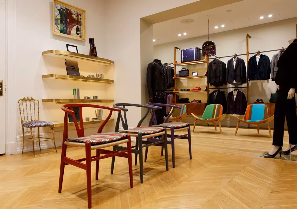 Sillas CH24 Wishbone de Carl Hansen & Søn en rojo y azul en una tienda de moda con suelo de espiga