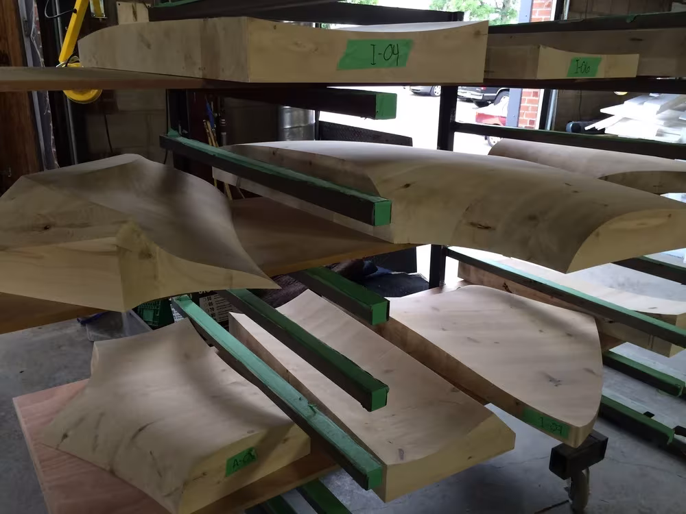 Piezas de madera curvadas apiladas en un carro del taller durante la construcción de la sauna Grotto