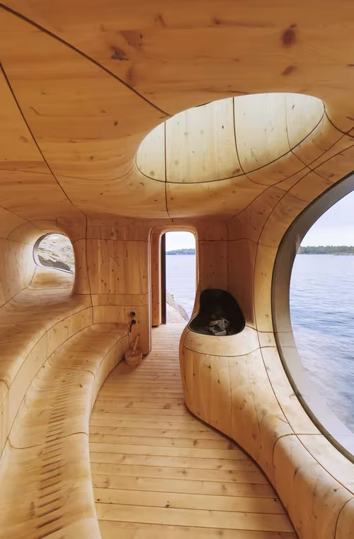 Pasillo de madera esculpida de la sauna Grotto con lucernario ovalado y vistas al lago