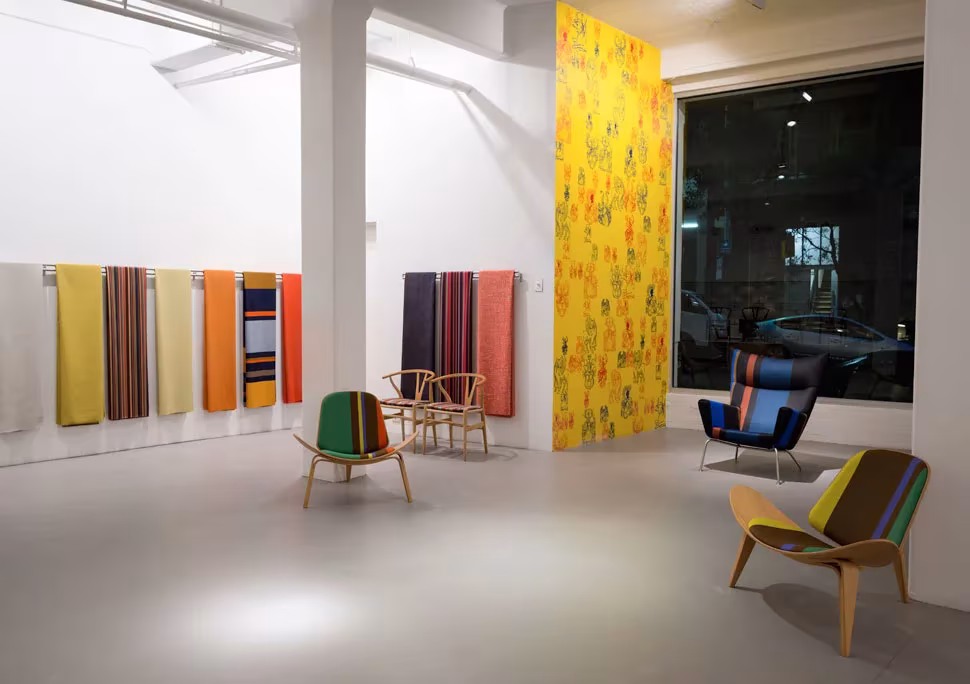 Sala de exposición de Carl Hansen & Søn con sillas de Wegner y tejidos de rayas de Paul Smith colgados