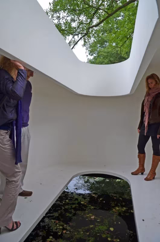 Interior blanco de la Sala de Agua de Rob Sweere con un hueco en el suelo hacia el agua y otro en el techo