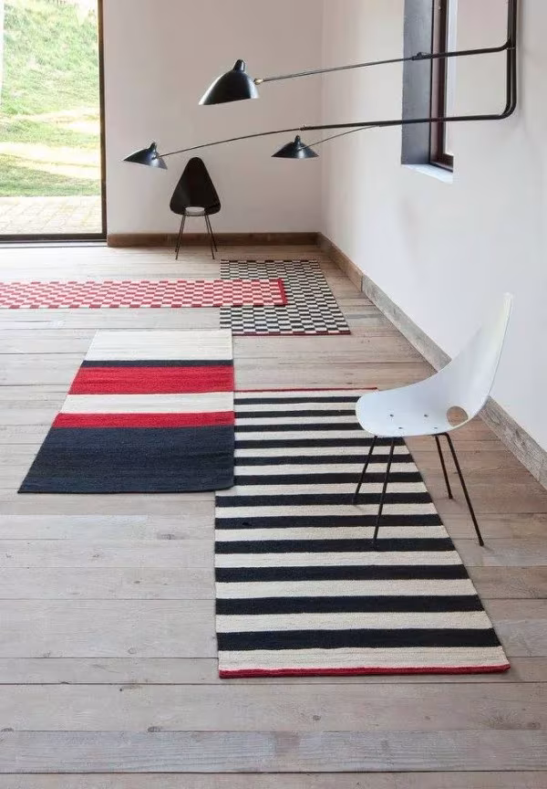 Alfombras Mélange alargadas a rayas rojas, negras y blancas en un pasillo con silla blanca