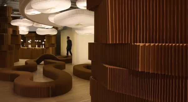 Espacio con biombos de cartón plegado y lámparas cloud de Molo Design colgadas del techo
