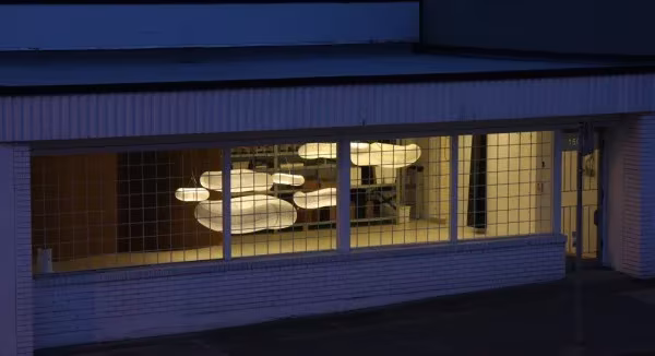 Escaparate nocturno con lámparas nube de Molo Design encendidas tras una ventana cuadriculada