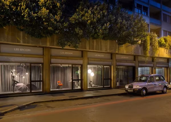 Fachada nocturna de «The Department Store» de Lee Broom en Milán, con escaparates iluminados y un taxi