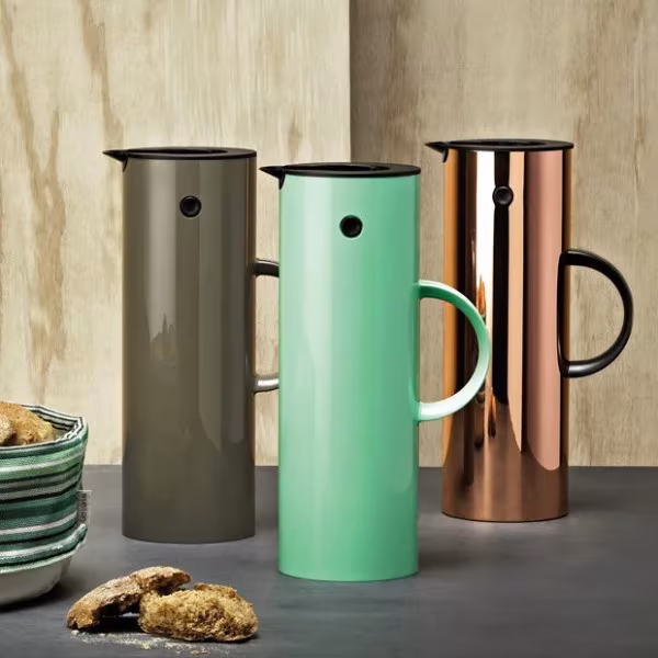 Tres jarras termo EM77 en gris, verde menta y cobre sobre una mesa con galletas