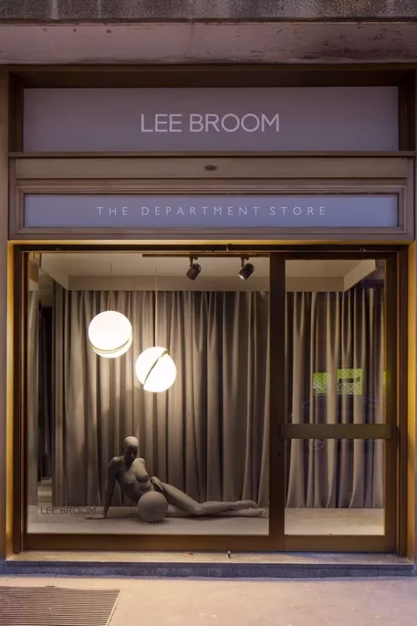 Escaparate de Lee Broom con lámparas de globo encendidas y una figura recostada tras el cristal