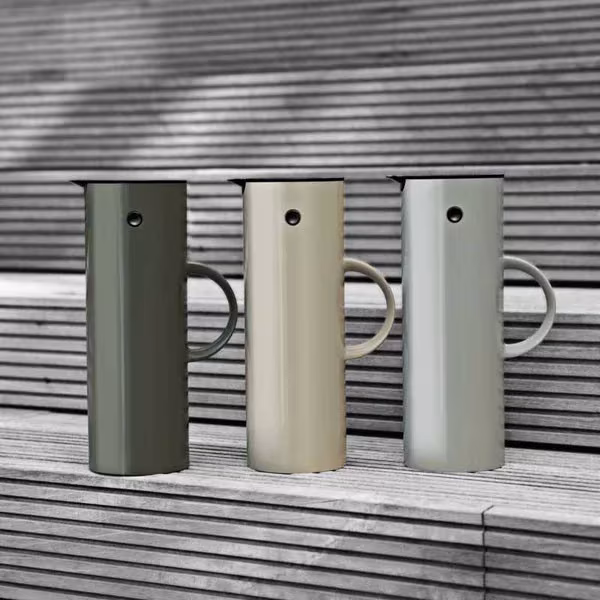 Tres jarras termo EM77 en verde oliva, beige y gris claro sobre listones de madera