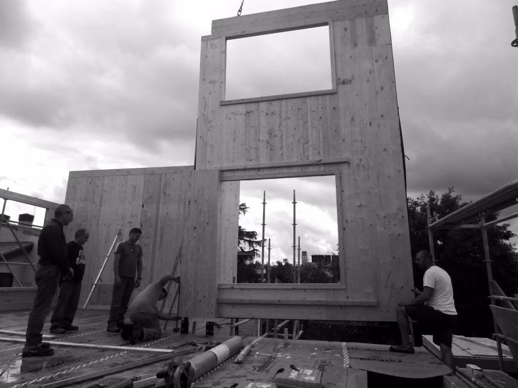 Montaje en obra de los muros de madera maciza de la Casa Ábaton de Aravaca con huecos de ventana recortados