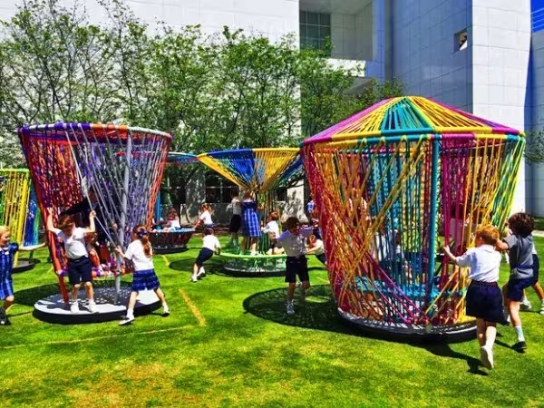 Niños jugando y girando los trompos tejidos de colores sobre el césped del High Museum de Atlanta