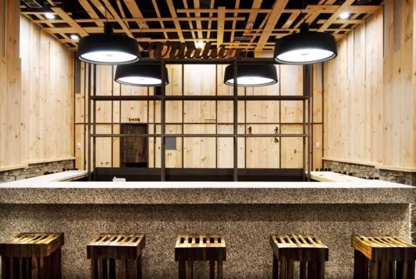 Barra de restaurante con revestimiento de madera y lámparas colgantes negras de Marset