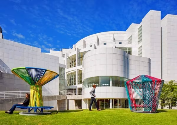 Trompos tejidos en el césped ante el edificio blanco del High Museum de Atlanta bajo un cielo azul