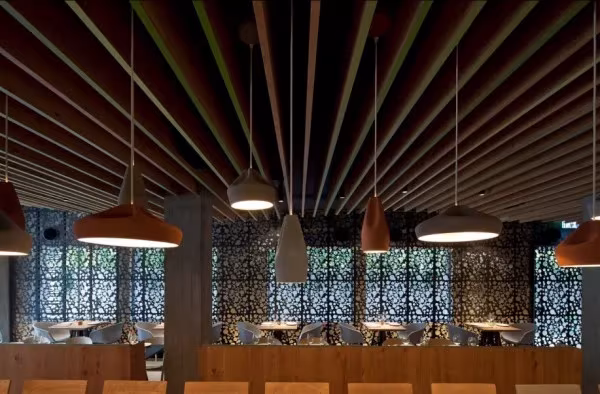 Restaurante Bindella con techo de listones de madera y lámparas colgantes de Marset en tonos cobre