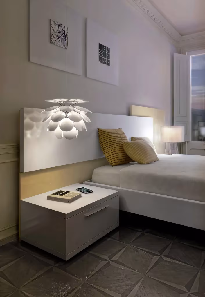 Dormitorio de hotel con la lámpara Discocó de Marset sobre la cama y mesilla blanca