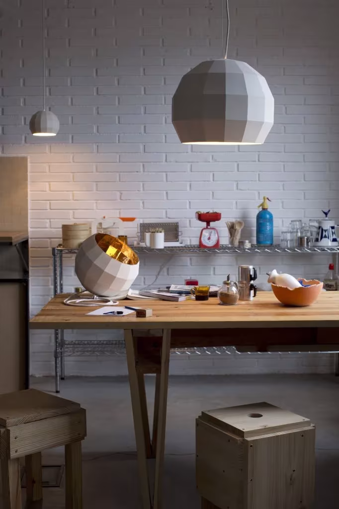 Cocina con lámpara Scotch Club blanca de Marset, mesa de madera y pared de ladrillo pintado