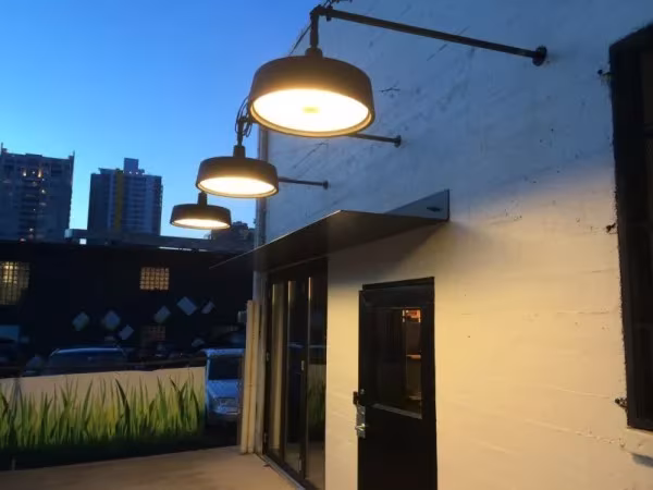 Apliques exteriores de Marset encendidos en la fachada de un edificio al anochecer