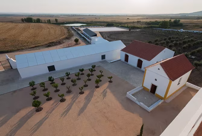 Vista aérea del conjunto agrícola rehabilitado de Torre de Palma, con tejados rojos, patio con olivos y campos alrededor