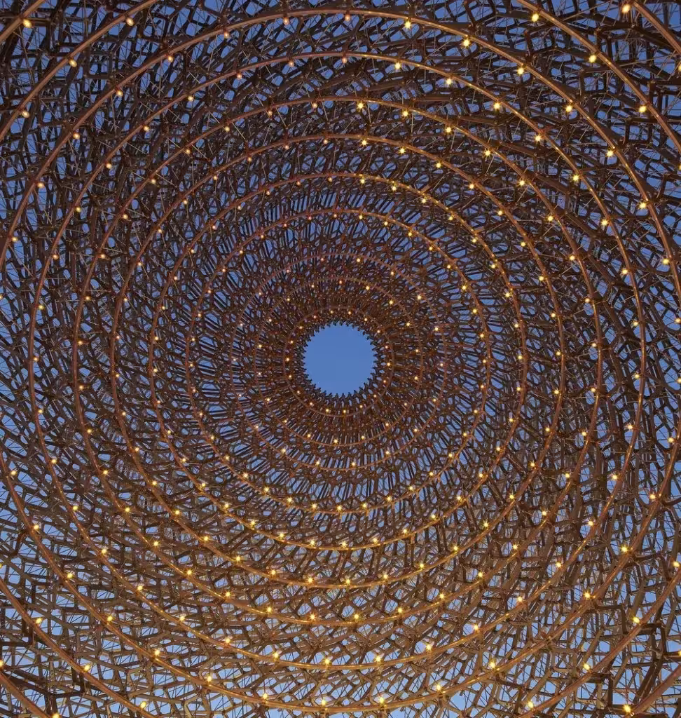 Vista cenital del interior de La Colmena, entramado metálico en espiral con luces y un óculo abierto al cielo