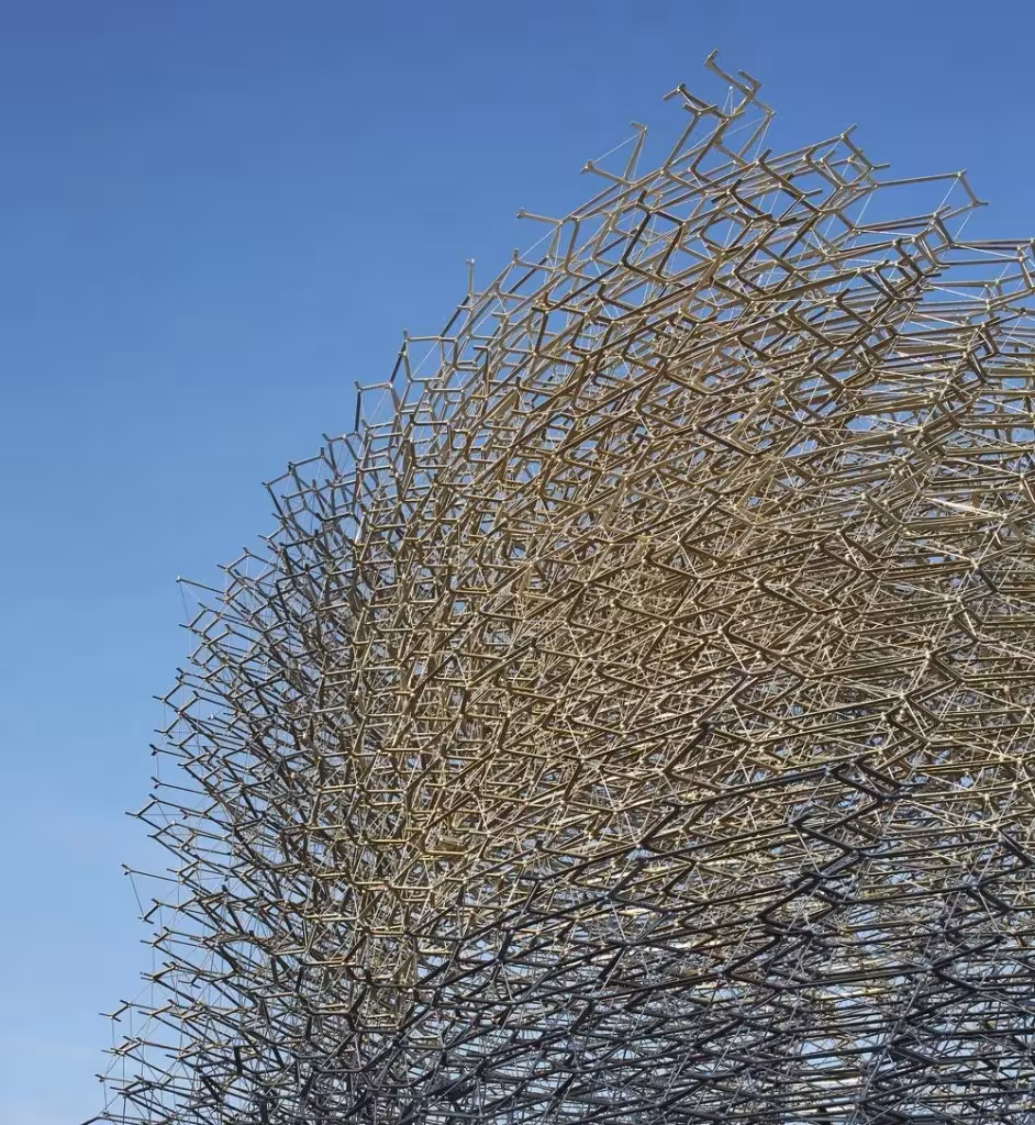 Malla de varillas metálicas hexagonales de La Colmena, pabellón de Reino Unido, recortada contra un cielo azul