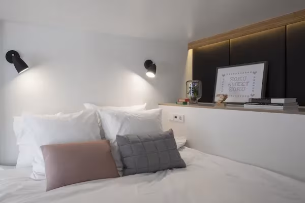 Cama con cojines y apliques negros en un loft ZOKU de Ámsterdam