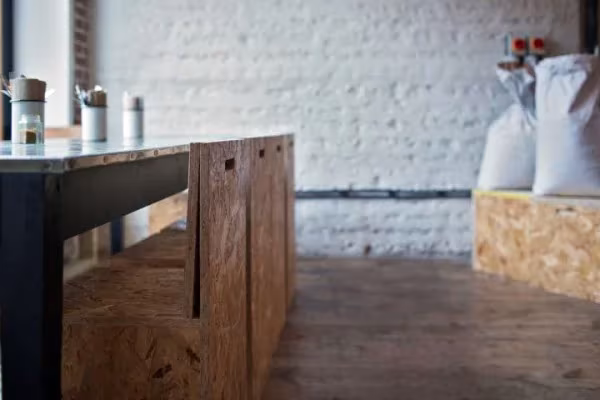 Barra de madera aglomerada y pared de ladrillo encalado con sacos de harina en el restaurante Silo