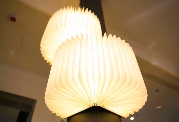 Dos lámparas Lumio abiertas en semicírculo emitiendo luz cálida en un interior en penumbra