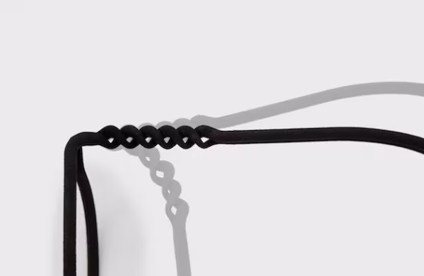 Detalle de la bisagra trenzada de unas gafas MONO negras impresas en 3D proyectando su sombra