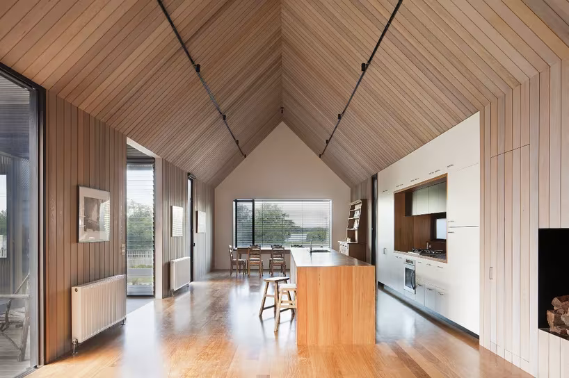 Espacio de cocina y comedor de Seaview House con techo de listones a dos aguas, suelo de madera y ventanal al fondo