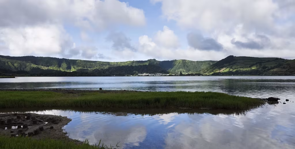 Lago de Sete Cidades en las Azores rodeado de colinas verdes y nubes reflejadas en el agua