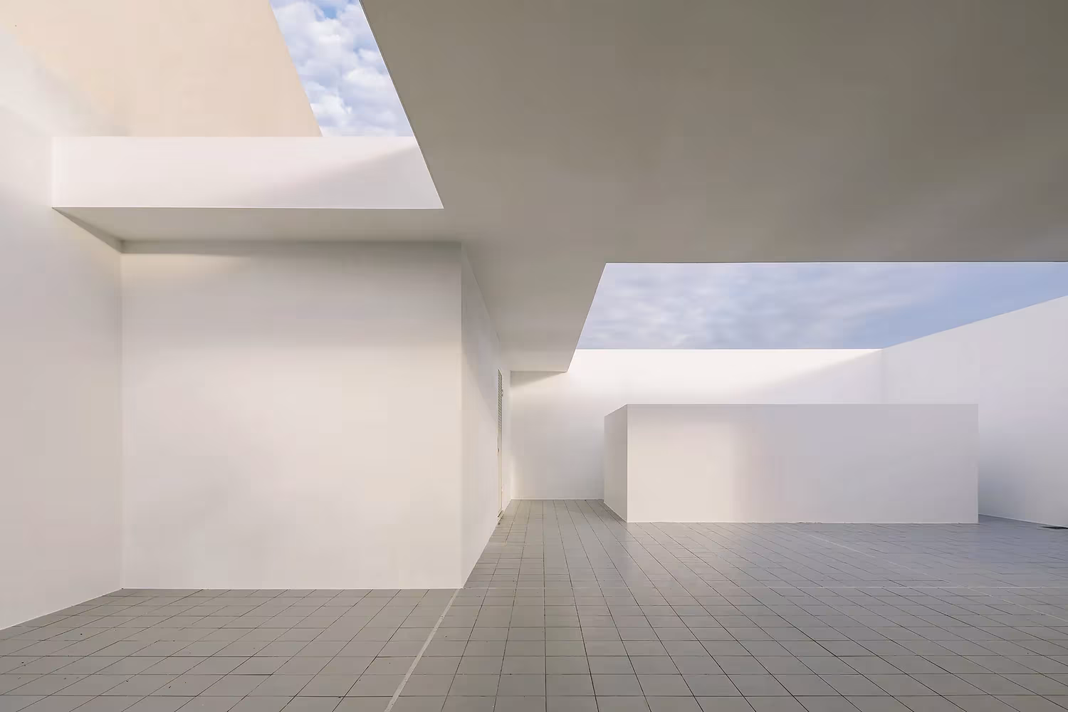 Patio interior blanco abierto al cielo con losas de gres en la Casa Brotero de phdd arquitectos, Lisboa