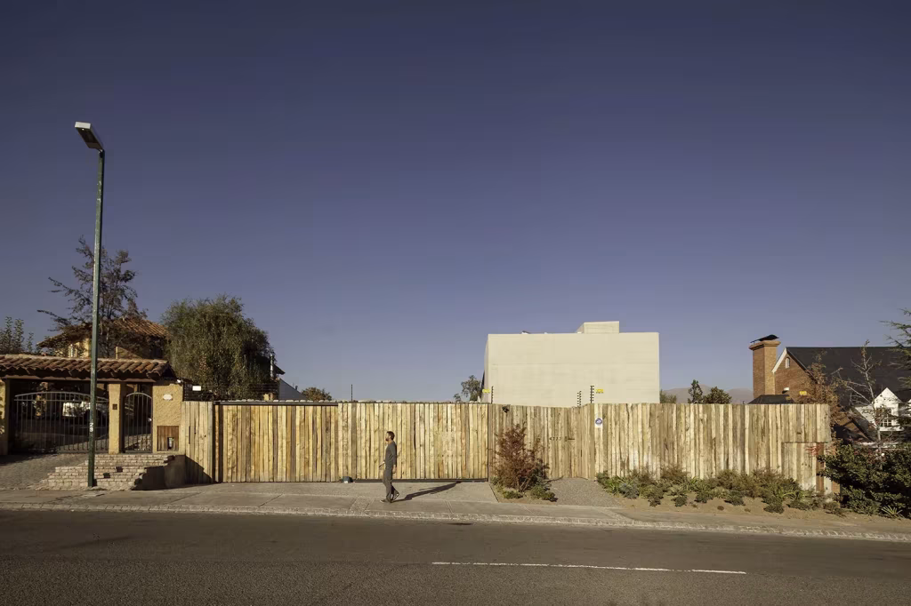 Calle frente a la parcela de la Casa SH antes de la obra, con valla de troncos de madera y farola