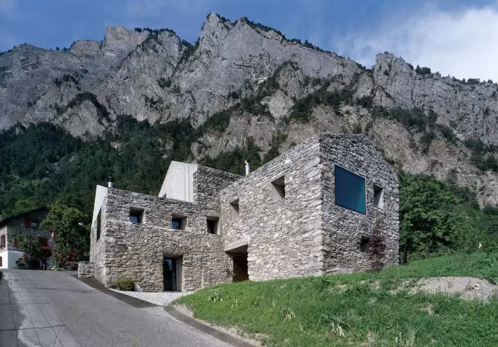 Vivienda rural de piedra renovada por Savioz Fabrizzi en Suiza, a los pies de una montaña rocosa