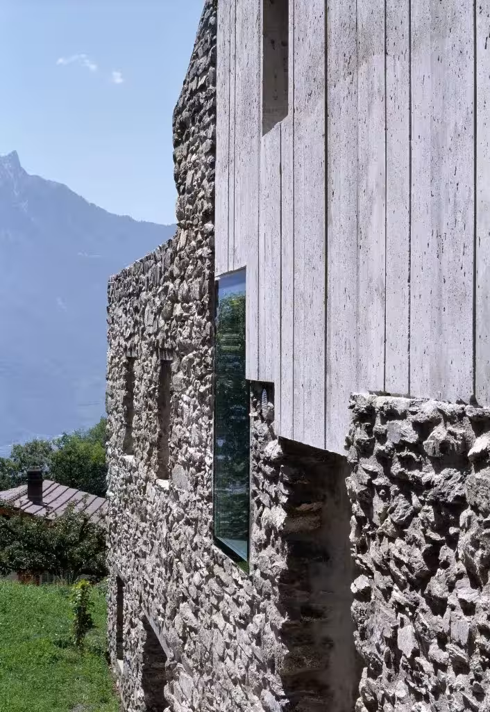 Encuentro entre el muro de piedra original y el nuevo hormigón encofrado con tablas en la fachada de Savioz Fabrizzi