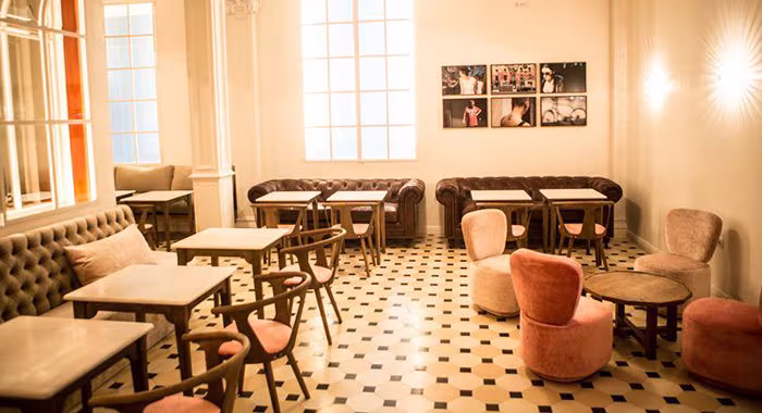 Sala del restaurante Lateral en Barcelona con mesas de madera, sofás de cuero marrón y butacas tapizadas en rosa