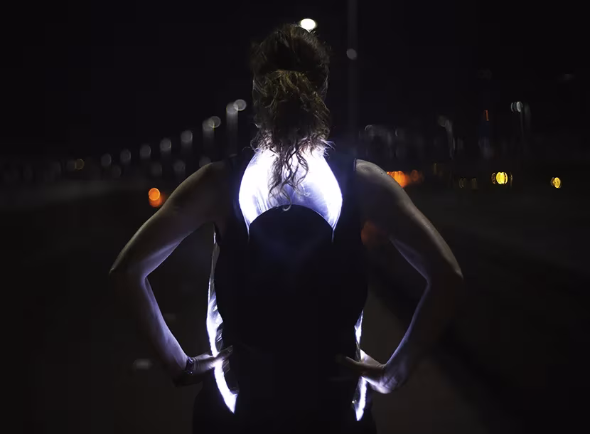 Espalda de una corredora en la oscuridad con la camiseta Phototrope de Pauline van Dongen brillando