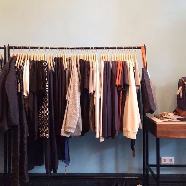 Perchero metálico con prendas en tonos tierra y oscuros en la boutique sostenible Möon de Berlín